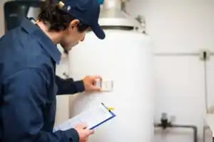 Plumber checking a tank water heater with a clipboard